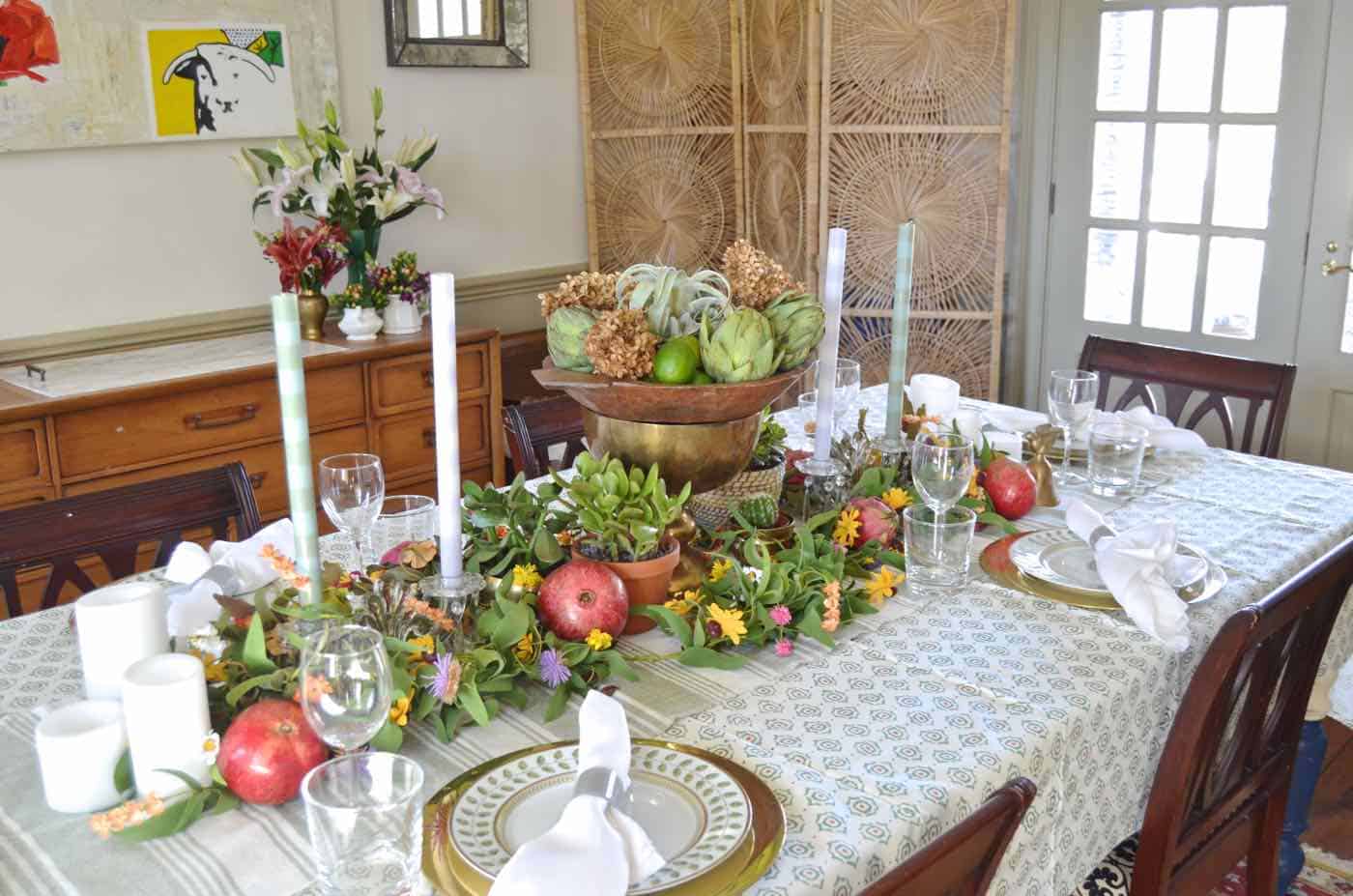 Thanksgiving tablescape with lush greenery and vegetables.