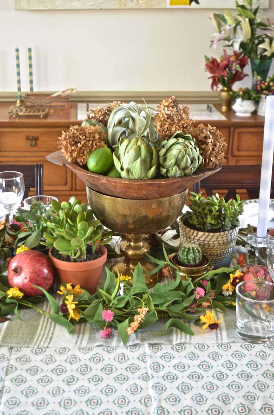 Thanksgiving tablescape with lush greenery and vegetables.