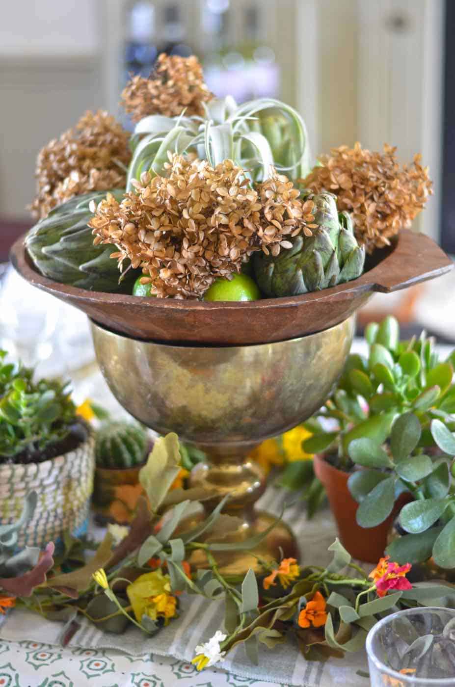 Thanksgiving tablescape with lush greenery and vegetables.