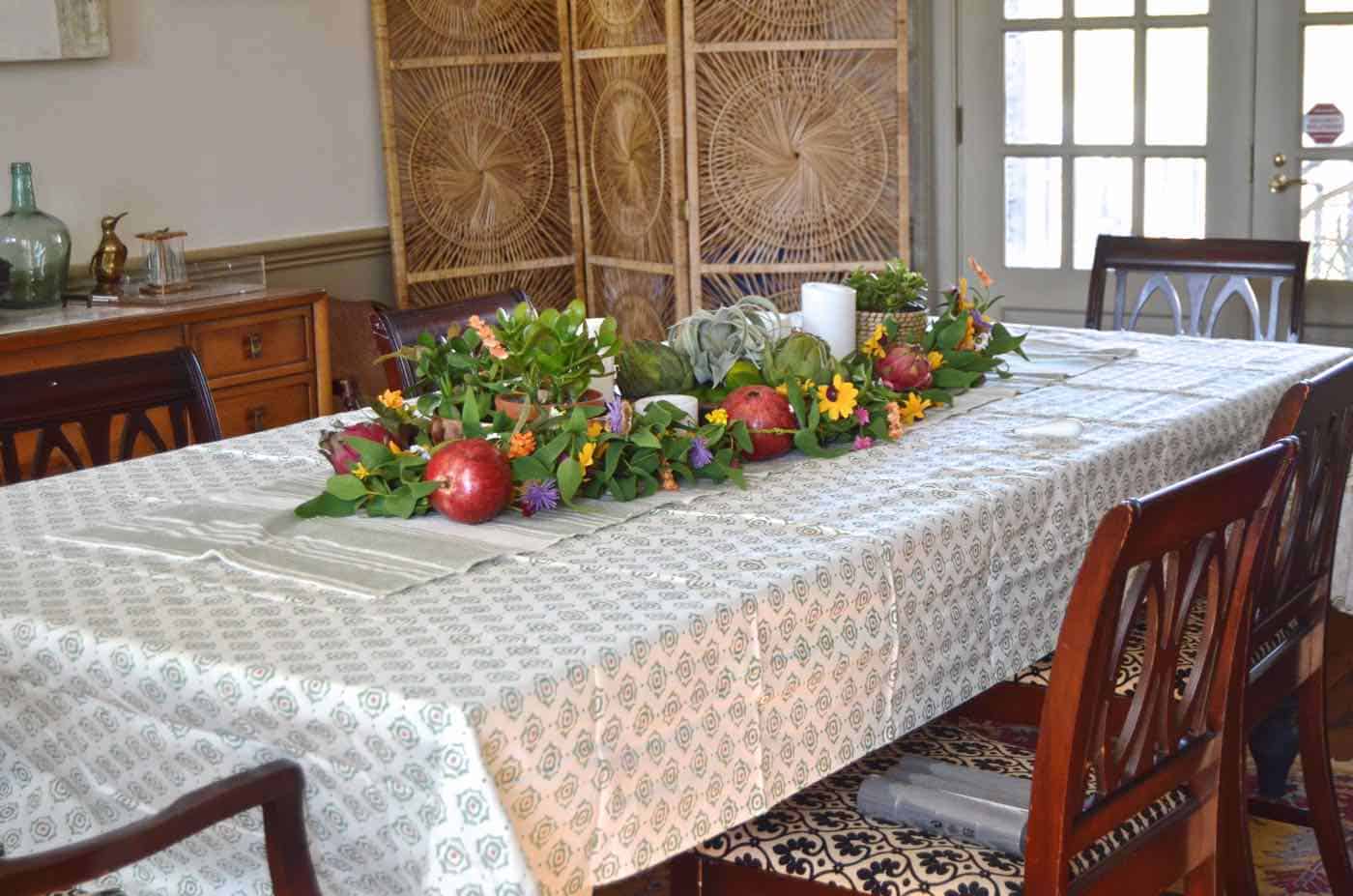 Thanksgiving tablescape with lush greenery and vegetables.