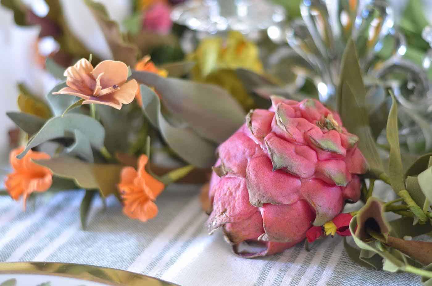 Thanksgiving tablescape with lush greenery and vegetables.