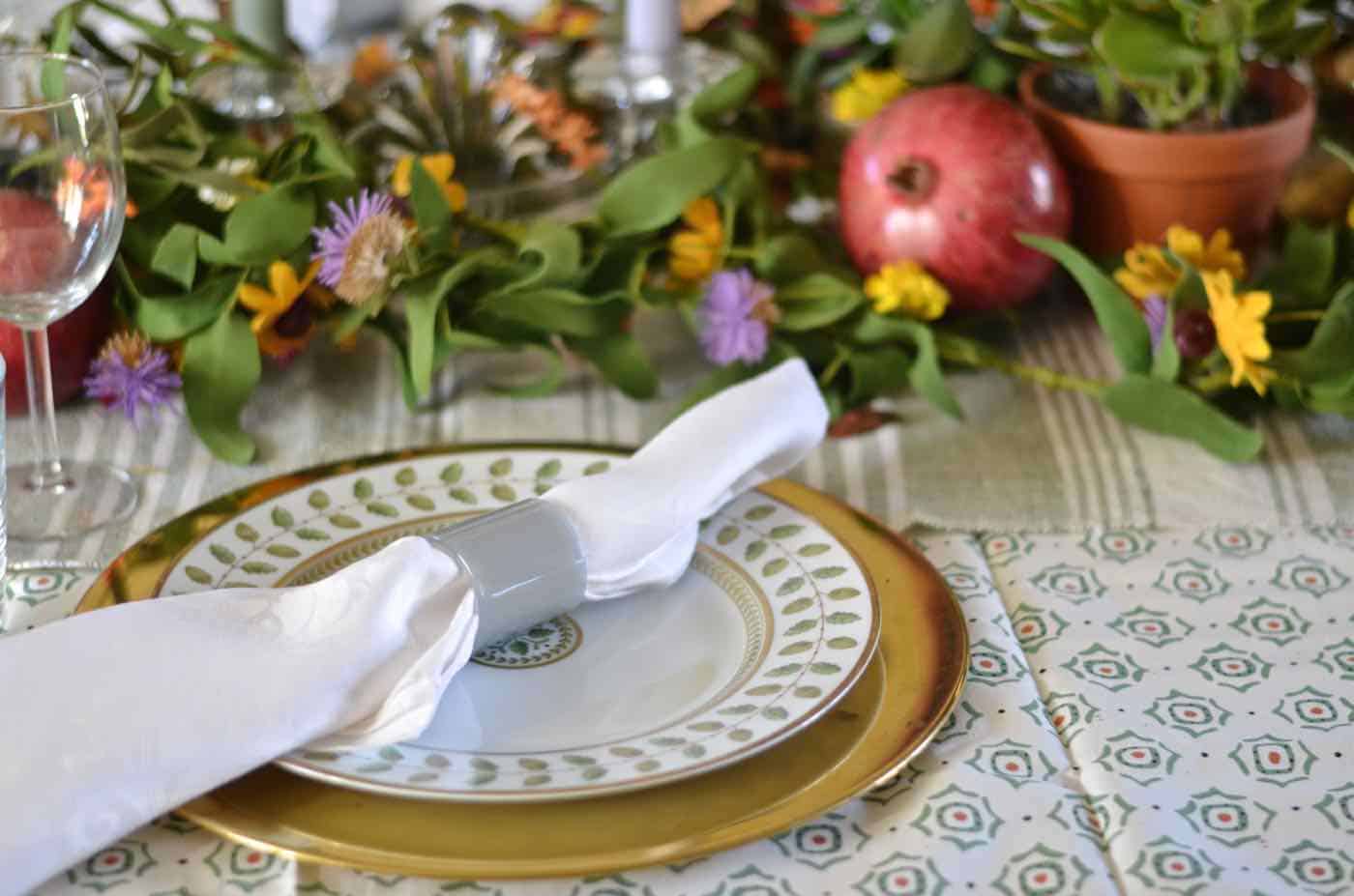 Thanksgiving tablescape with lush greenery and vegetables.