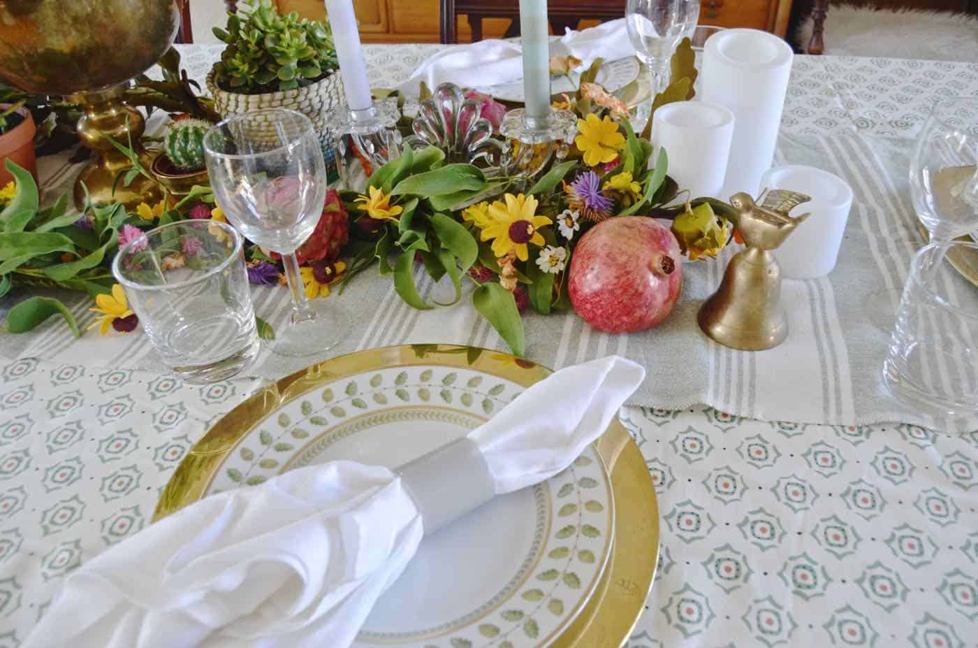 Thanksgiving tablescape with lush greenery and vegetables.