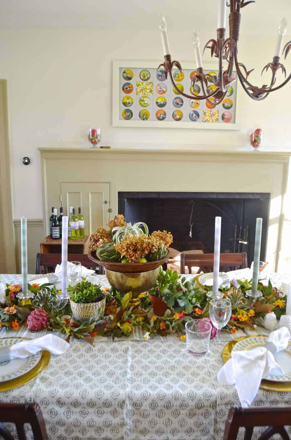 Thanksgiving tablescape with lush greenery and vegetables.