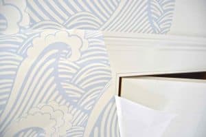 Doors and windows are always the challenge with wallpaper. I'm NO expert, but what worked best for me was to trim away as much of the excess paper as I could and then make release cuts into the corners. But there was definitely some cursing involved at times.