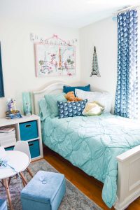 bed in girls room with pillows and canvas art hanging above