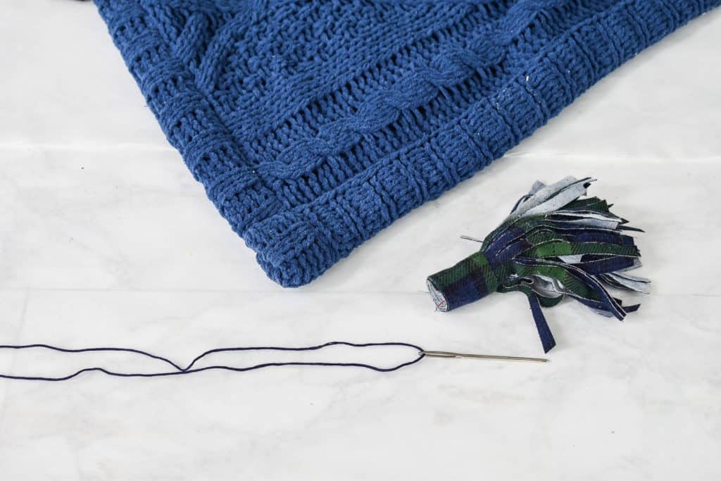 sew the tassel onto the blanket with embroidery thread
