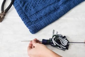 sew the tassel onto the blanket with embroidery thread