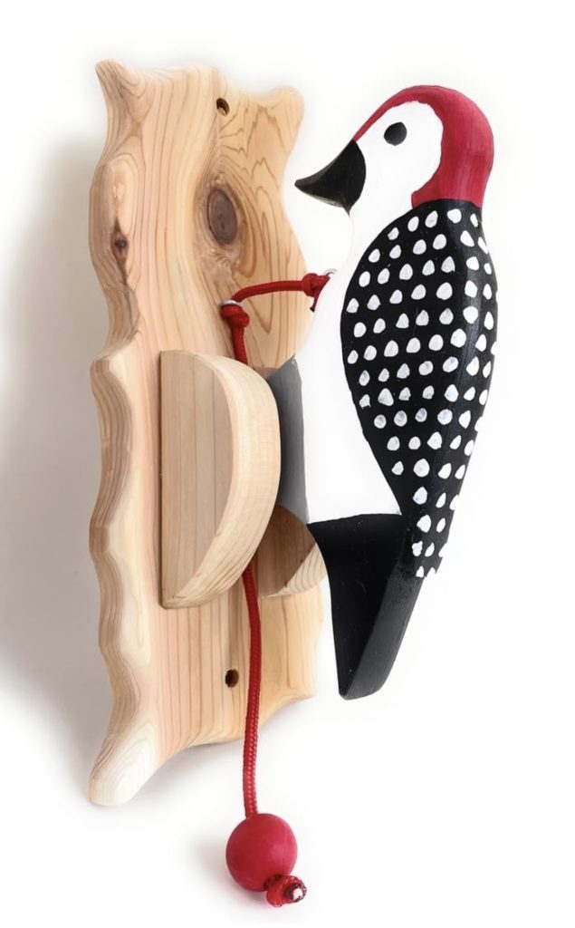 red and black wooden door knocker shaped like a woodpecker