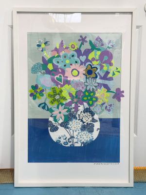 A framed artwork featuring a decorative vase filled with an array of colorful flowers, including blue, purple, and green hues. Some flowers have heart-shaped petals, and the background consists of subtle blue and gray tones.