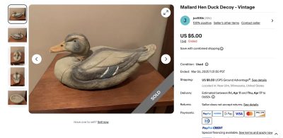 A wooden mallard hen duck decoy is displayed on a wooden surface. The decoy has detailed painting to resemble a duck, with a realistic color scheme. A "SOLD" banner is across the image. The listing shows a $5 price with shipping details.