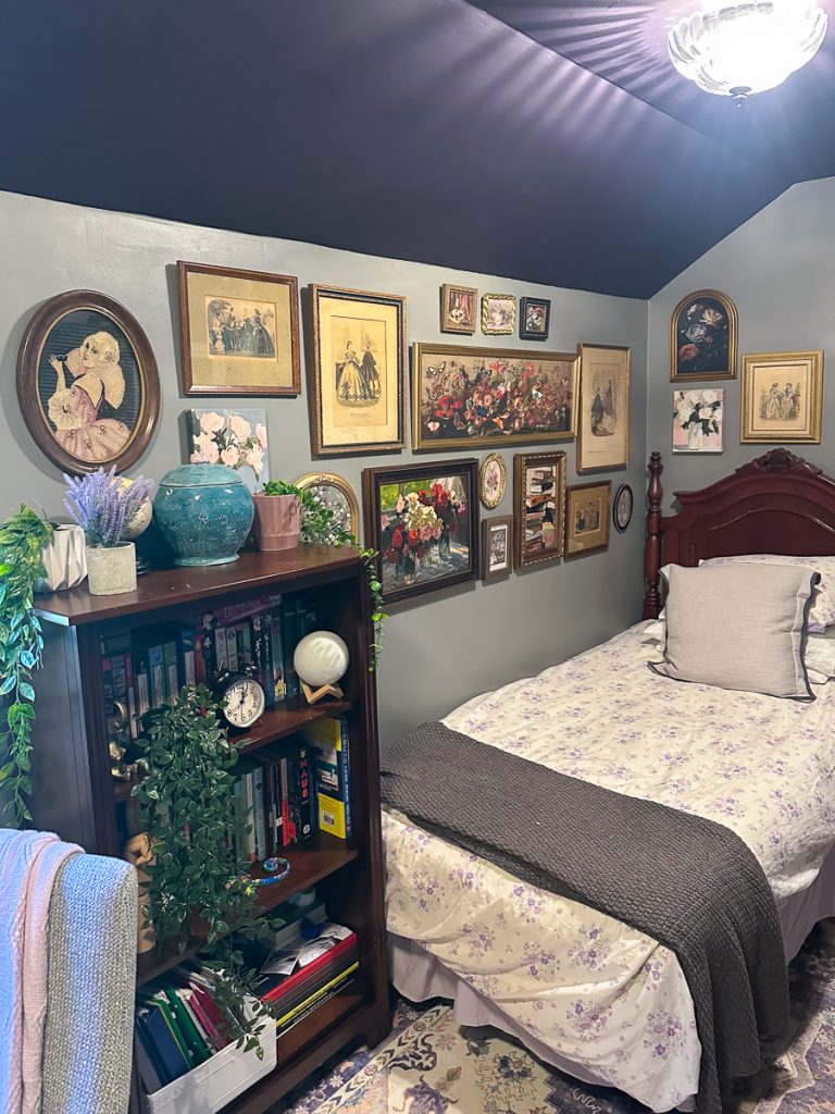 A bedroom featuring a bookshelf filled with decor and books, next to a twin bed with floral bedding and a gallery wall of assorted framed art.